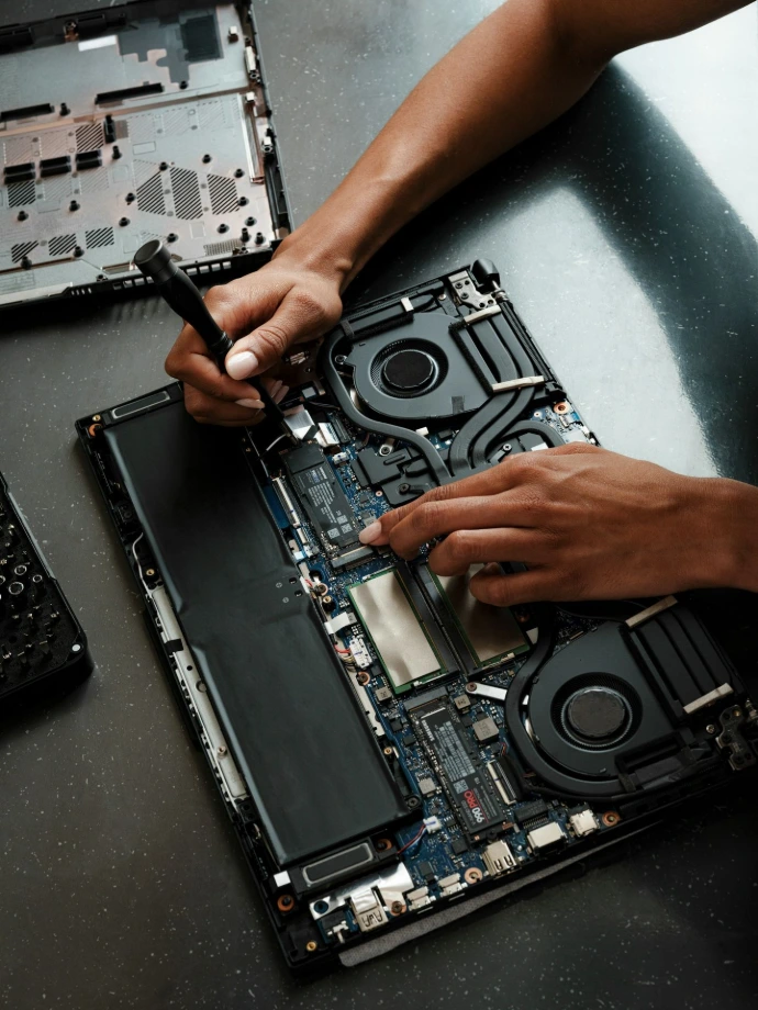 A person working on a laptop with a screwdriver
